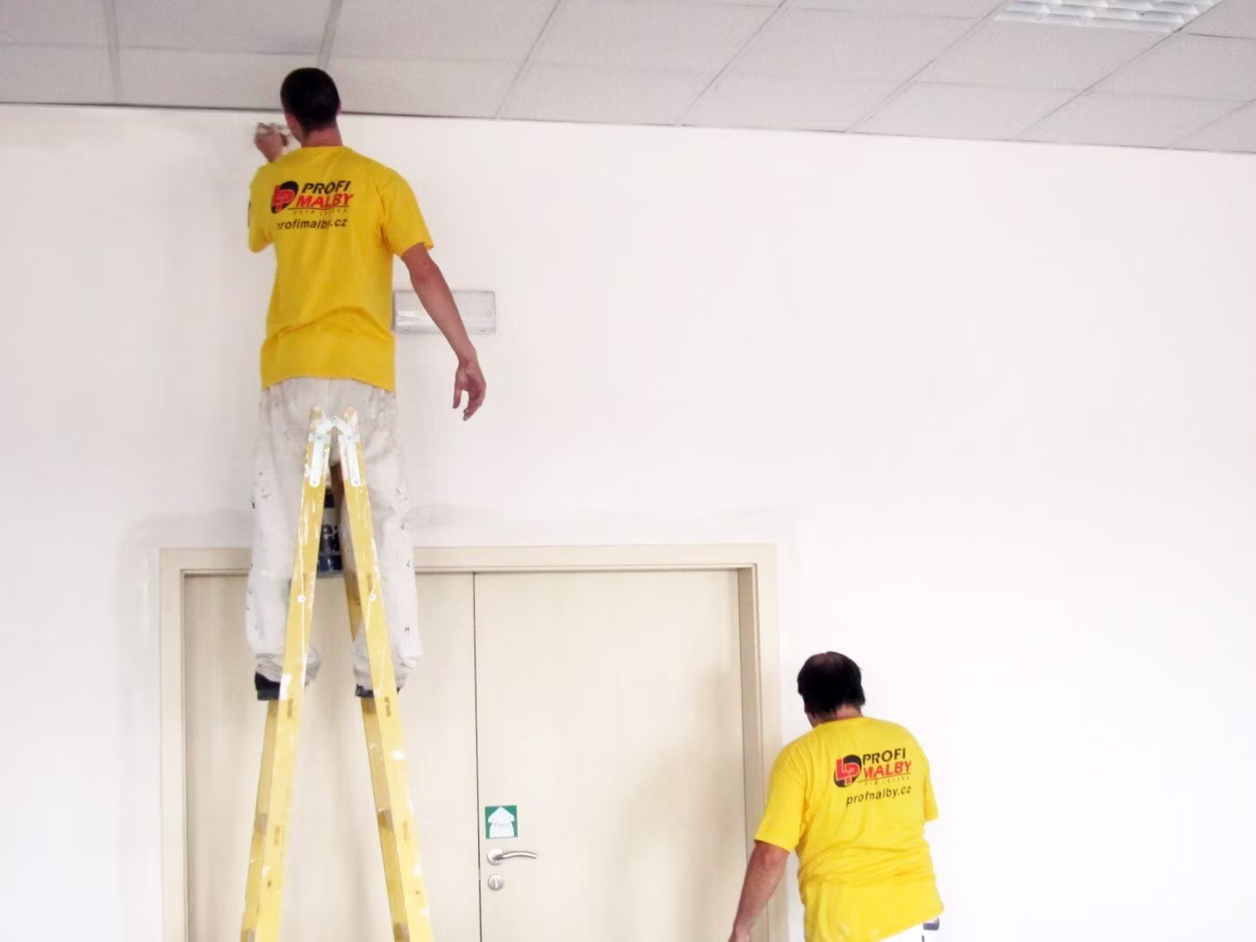 Profesionální malíři z Profimalby pracují na malování stěny